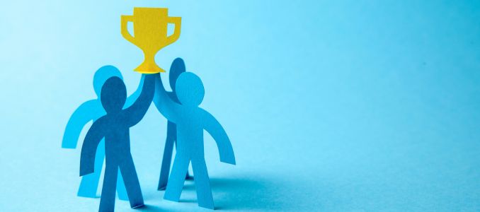 Paper cut outs of Successful business team winner holding gold cup in his hands