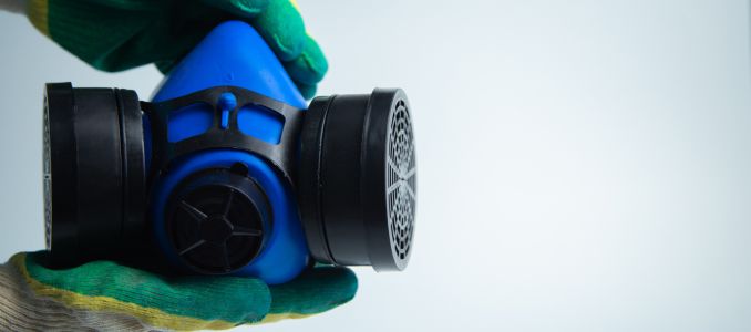 Hands in construction gloves holding a protective blue mask with two filters on a white background