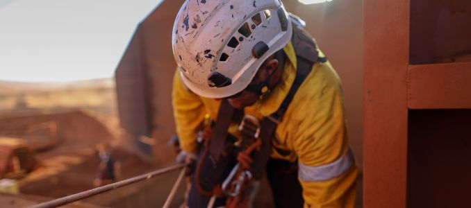 Rope access industry abseiler welder wearing safety full protection helmet while working at height construction site
