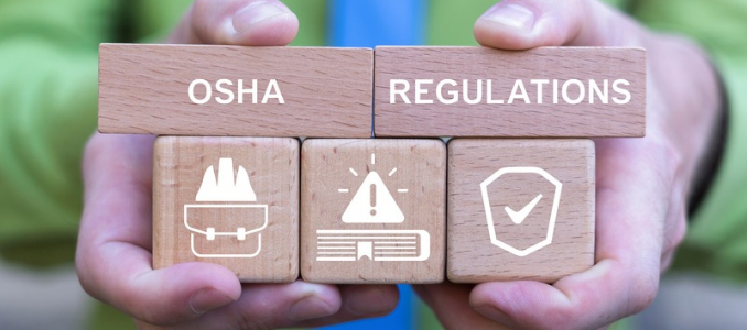 Hands holding wooden blocks spelling out "OSHA REGULATIONS" above icons representing workplace safety, rules, and compliance.
