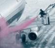 A ground crew member sprays deicing fluid on a passenger jet before takeoff.