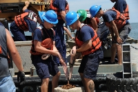 This U.S. Coast Guard/Petty Officer 3rd Class Kelly Parker photo shows Coast Guard personnel and civilian contractors setting protective boom in place June 16 on Raccoon Island, a protected bird breeding sanctuary about 20 miles south of Cocodrie, La. 