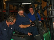 Larry Dobson, an experienced hi-lo driver, helps Mark Westrate with practical training on the machine as Safety Manager David Cox observes. (Dave Edwards/Grand Valley State University photo)
