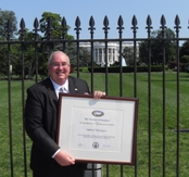 Carlos Lemos, president and CEO of Ambient Technologies, Inc., poses outside the White House with the Presidential 