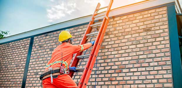 a person in an orange jumpsuit climbs up an orange ladder on the side of a brick building