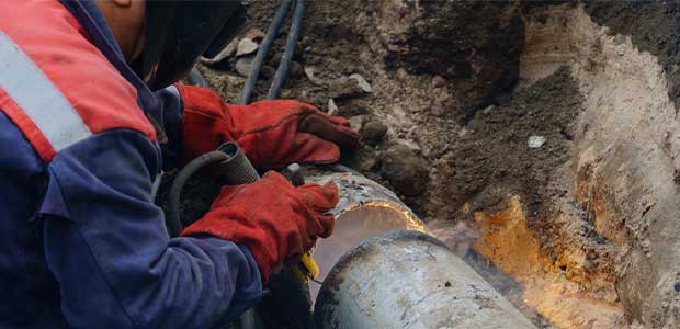 hands working on a broken pipe underground