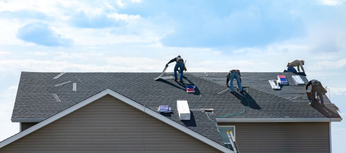 4 construction workers fixing roof against clouds blue sky