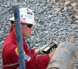 An oil and gas emegency planner takes air samples at the test valve to determine whether hydrogen sulfide is present during drilling operations.