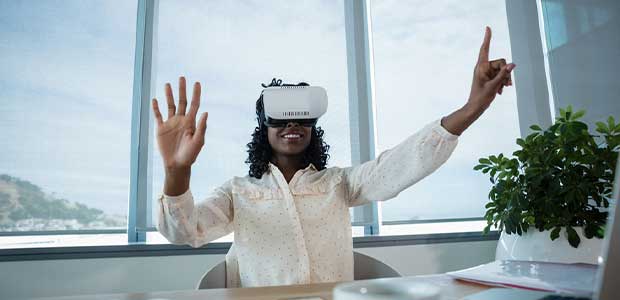 a women with a virtual reality headset on sits at a desk