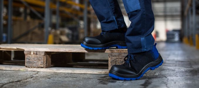 Warehouse Worker in Safety Shoes Standing on Wooden Pallet