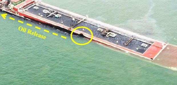 The U.S. Coast Guard photo, taken on March 22, 2014, the day of the collision, shows the damaged fuel oil barge leaking oil, with its bow submerged. The tugboat