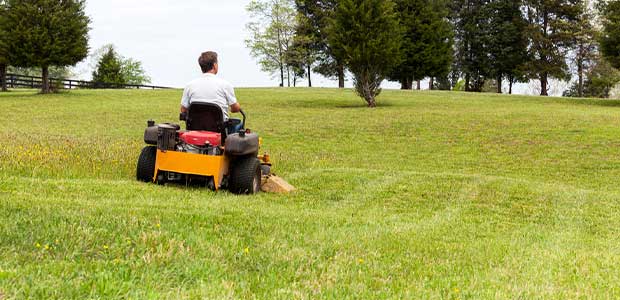 person driving a mower in a large field