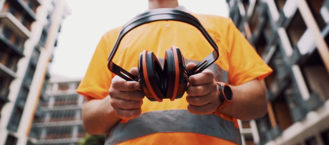 Construction worker holding ear muffs