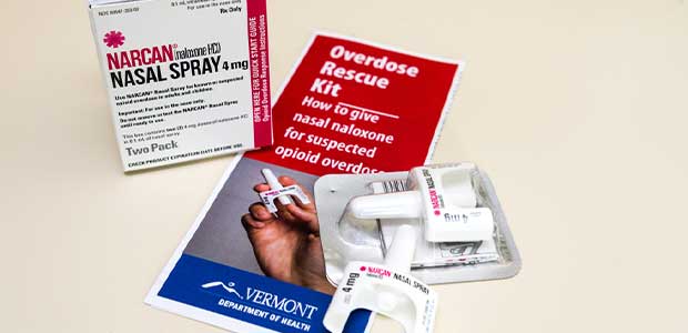 a box for Narcan spray sits on top of a leaflet reading "Overdose Rescue Kit." There are two units of Narcan on top of the leaflet.