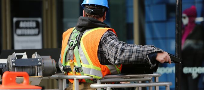 Construction worker in safety vest and blue hard hat working on scaffolding with high visibility, construction site