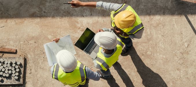 Three construction workers huddled together