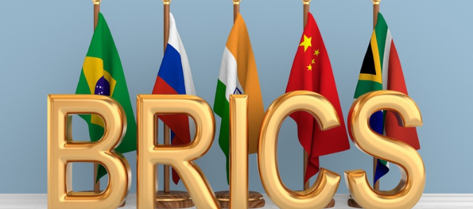 Large 3D gold letters spelling BRICS in front of the national flags of Brazil, Russia, India, China, and South Africa.