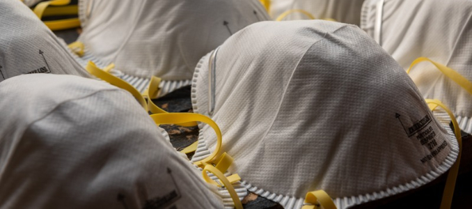  Rows of white N95 filtering facepiece respirators with yellow straps.