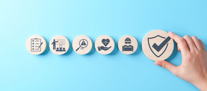 Wooden blocks safety-related icons, including compliance, health, inspection, training, protection, regulatory