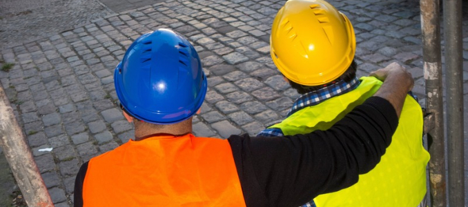One construction worker places a supportive arm around a colleague at a jobsite.