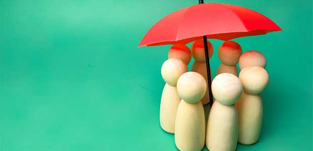 eight wooden dolls standing under a red umbrella with a teal background