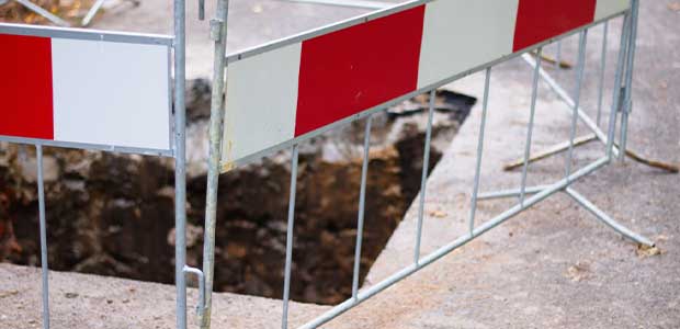 an up-close view of red and white barriers around a square hole in the ground