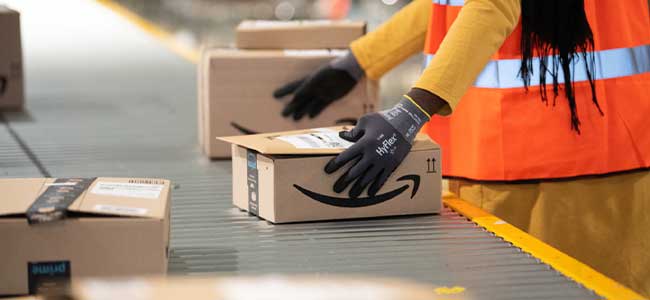 a person in an orange safety vest moves two amazon boxes along a conveyor belt