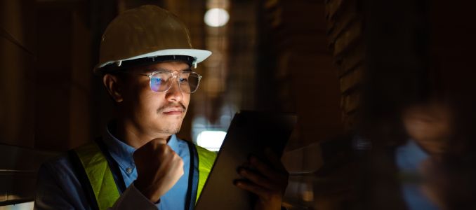 Engineer on night shift in warehouse holding tablet