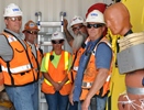 Some of the original first responders in the equipment conex trailer are (from left to right): casting yard Manager Bob Wheeler; carpenter General Foreman Bobby Miller; site EMT Melissa Crisman; ironworker Superintendent Glen Bragg; and batch plant Superintendent Rich Hamilton. The crash dummy is used for rescue drills that train personnel to remove an injured worker on a stretcher. (U.S. Army Corps of Engineers photo)