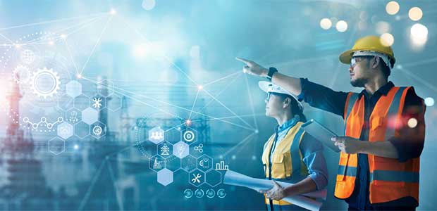 two people in vests and hard hats look into the distance where connecting lines sit overtop of a working plant