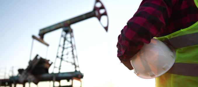 Oil rig worker holding hard hat on site