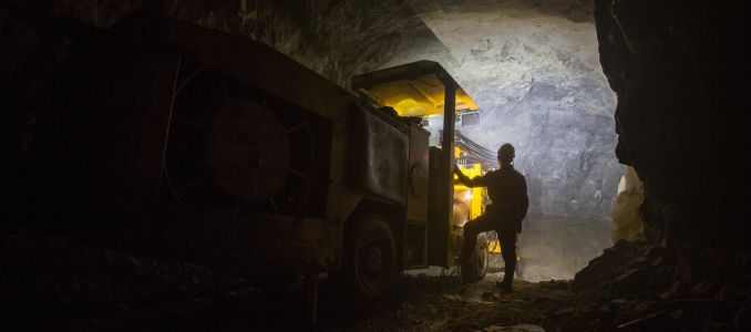 Miner standing next to drilling equipment