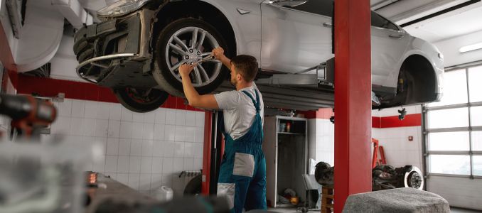 Worker screwing auto wheel on car service station