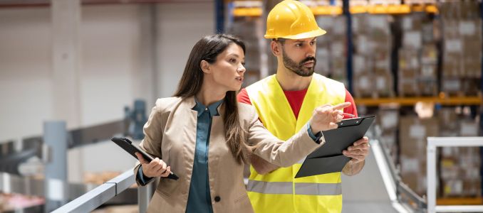 manager explains safety procedures to a safety officer in the warehouse