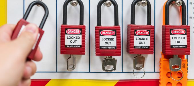 Safety Lockout tagout station with hanging locks with keys and hand of technician putting lock on the station