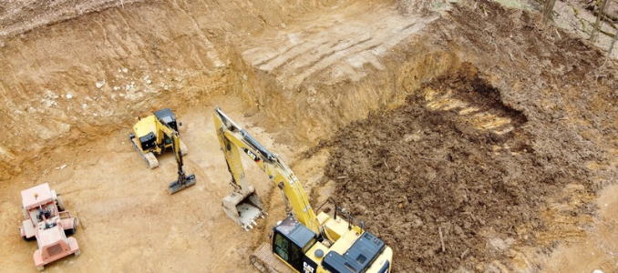 High-angle view of excavators operating in a large earthen excavation site.