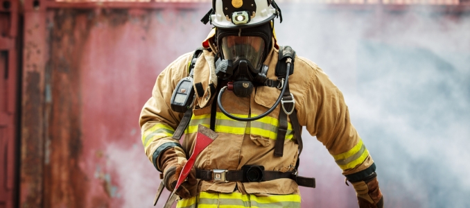 Firefighter wearing breathing mask standing in smoke during emergency operation