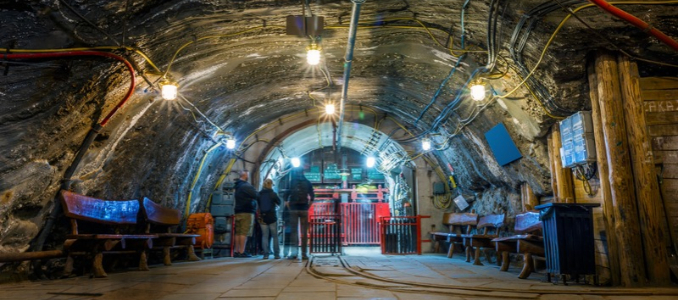 Workers walking through an illuminated underground salt mine tunnel.