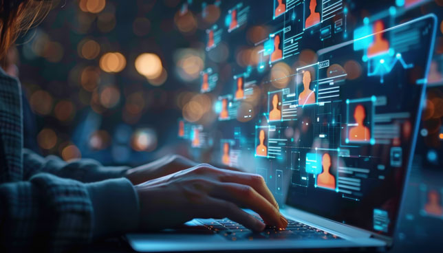 A person types on a laptop surrounded by floating digital profiles