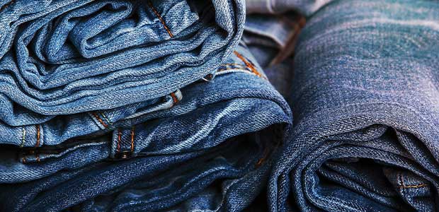 pile of rolled-up blue jeans