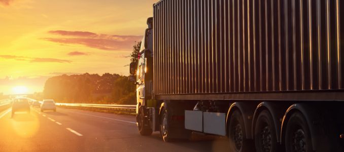 Truck driving on road during sunset