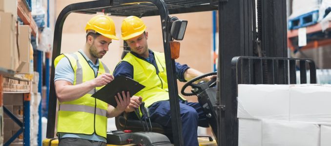 Warehouse worker talking with forklift driver